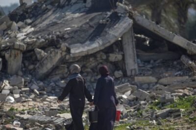 Mujeres palestinas desplazadas caminan frente a una estructura destruida por los bombardeos israelíes en el sur de la Franja de Gaza.